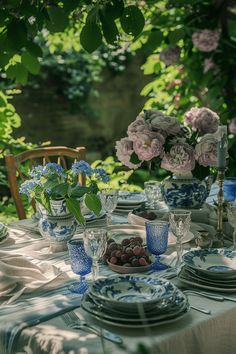 the table is set with blue and white plates, cups, and vases filled with flowers