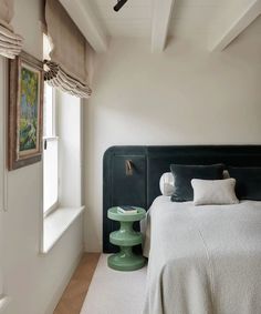 a bedroom with a bed, nightstand and window in the corner on the side wall