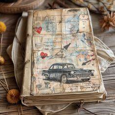 an old book is sitting on a table with dried flowers and other things around it