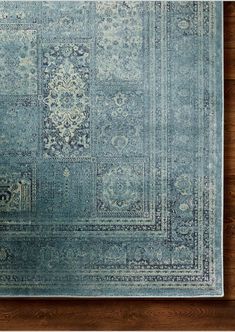 a blue area rug with an intricate design on the top and bottom, in front of a wooden floor