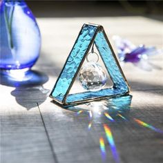 a triangle shaped object sitting on top of a wooden table next to blue vases