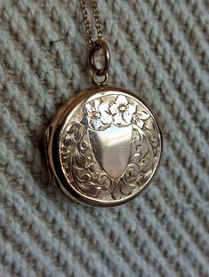 Lovely mid-century locket with a rose gold hue and fine engravings on both sides. A plain cartouche at the front could be engraved with initials or stay as is. It is surrounded by buttercup flowers and foliage. Details: The locket dates from the 1950s and if from the UK. It is stamped at the back "9ct back and front". Condition: The locket is in excellent antique condition, with only gentle surface wear and patina. The two original rings are present inside. This listing is for the locket only wi Vintage 14k Gold Locket Necklace Stamped 14k, Vintage 14k Gold Locket Necklace, Vintage Rose Gold Locket Necklace For Wedding, Victorian Engraved Rose Gold Locket Necklace, Vintage Etched Rose Gold Jewelry, Rose Gold Vintage Charm Locket Necklace For Wedding, Vintage Rose Gold Etched Jewelry, Vintage Stamped 14k Locket Necklace For Wedding, Vintage 14k Gold Locket Necklace With Vintage Charm