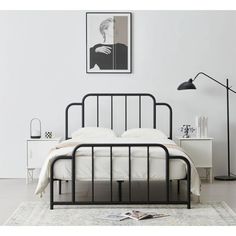 a black metal bed frame in a white bedroom