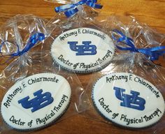 four decorated cookies in plastic wrappers on a wooden table with blue ribbon around them