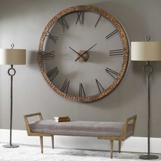 a large clock mounted to the side of a wall next to a bench and lamp