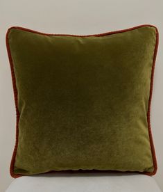 a green and orange pillow sitting on top of a white chair