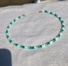 a green and white beaded bracelet sitting on top of snow covered ground