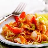 a white plate topped with pasta and veggies next to a knife and fork