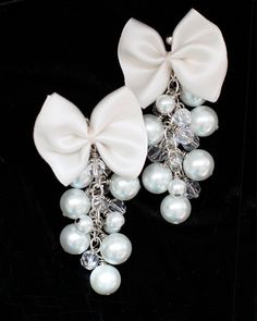 "Finish-off a whimsical ensemble with a pair of feminine and chic pearl and bow dangle earrings!! These stunning earrings feature darling satin bows, hand-sewn together, and finished with a cascade of glass pearls and crystal beads...An instant dose of style!! Cute enough for day; fancy enough for bridal!! Wouldn't this item make a lovely bridesmaid accessory?! ♥Brass base metal. ♥Choose from gold or silver. ♥Glass pearls. ♥Available in: Aqua, Black, White, Ivory (shown), or Pink. ♥Satin bows. ♥ White Bow Earrings For Wedding, White Jewelry With Decorative Bow For Evening, White Evening Jewelry With Decorative Bow, Elegant Wedding Earrings With Ribbon, White Bow Earrings For Anniversary, Elegant Ribbon Earrings For Wedding, White Pearl Earrings With Bow For Party, White Bow Jewelry For Evening, White Pearl Earrings With Bow For Wedding