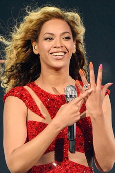 a woman in a red dress holding a microphone and making the peace sign with her hands