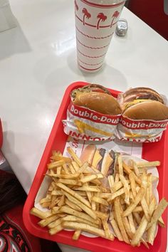 two trays filled with french fries and hotdogs next to a cup of soda