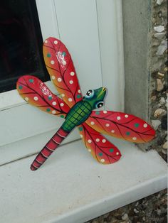 a red dragonfly sitting on top of a window sill next to a white door