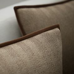 a close up view of a brown and white pillow on a couch with pillows behind it