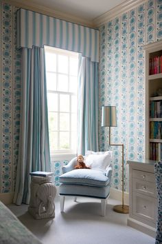 a teddy bear is sitting on a chair in the corner of a room with blue and white wallpaper