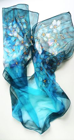 "Hand-painted 100 % silk scarf with wild flowers. Intense dark blue and turquoise shades with shining gold outlines. Perfect for beach wear or special occasions. Painted on Chiffon 3,5 pure silk. Chiffon is a diaphanous, translucent silk which works well with almost every dress. It flows like water when you wear it. Colors are more intense when it's layered.  Hand-rolled edges. Scarf is long enough to twist 3 times around the neck. Great for special occasion to drape freely around the shoulders. Size: 200 cm x 50 cm (78\" x 19\") The silk dyes are non-toxic and permanent, so the scarf is hand-washable.  ARRIVES GIFT-WRAPPED WITH FREE MATCHING GIFT CARD. WASHING INSTRUCTIONS INCLUDED IN  ENGLISH / FRANCE / ITALIAN / GERMAN LANGUAGE. International shipping takes about 4-15 days. Express deli Elegant Hand Painted Blue Silk Scarf, Blue Silk Scarf For Beach In Spring, Elegant Blue Silk Scarf For Beach, Hand Painted Blue Silk Scarf For Summer, Blue Hand Painted Silk Scarf, Blue Bohemian Hand Painted Silk Scarf, Blue Hand Painted Bohemian Silk Scarf, Bohemian Blue Hand Painted Silk Scarf, Artistic Blue Silk Scarf For Spring