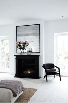 a white bedroom with a fireplace in the corner and a chair on the floor next to it