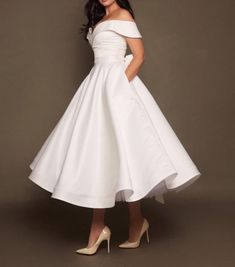 a woman in a white dress posing for the camera with her hands on her hips