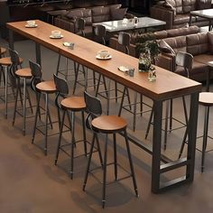 a long table with four stools next to each other in a room filled with couches and tables