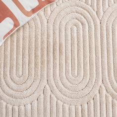 a beige rug with circles on it next to a pillow that has an orange and white design