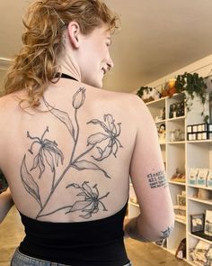 a woman with a tattoo on her back is looking at the shelves full of items