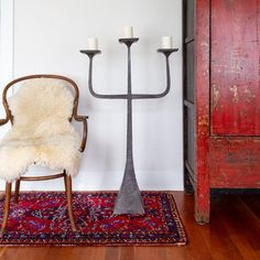 a chair sitting next to a tall candelabra on a rug in a room