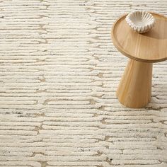 a wooden table sitting on top of a white carpeted floor next to a rug