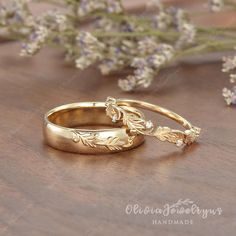 two gold wedding rings sitting on top of a wooden table next to lavenders and flowers