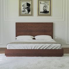 a bed with two pictures on the wall above it and white carpeted flooring