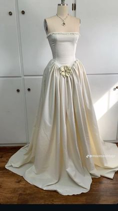 a wedding dress on display in front of a white cabinet