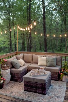 a couch and ottoman on a deck with string lights