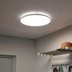 a light that is on above a shelf in a room with clothes hanging from it