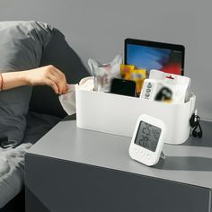 an alarm clock sitting on top of a table next to a laptop computer and other items