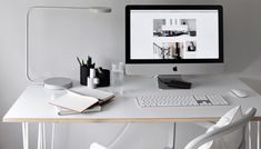 a computer monitor sitting on top of a white desk next to a keyboard and mouse