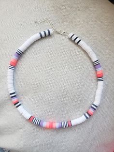 a multicolored necklace is displayed on a white cloth surface with a silver chain