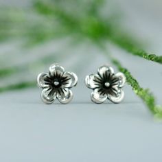 These Cherry Blossom Stud Earrings feature a beautiful nature-inspired flower design. In Japan, the Cherry Blossom is a reminder that life is beautiful, but can be very short, and that we must enjoy all our moments. We are happy to create these earrings for you in a variety of finishes. These delicate Sterling Silver stud earrings measure 7 mm in width, and have a 4 mm (.15 inch) long sterling silver post. They come complete with Sterling silver ear backs and a box appropriate for gift giving. T Sterling Silver Birth Flower Earrings, Nature-inspired Sterling Silver Flower Earrings, Botanical Flower Earrings With Flower Charm, Nature-inspired Hypoallergenic Flower Earrings For Gift, Nature-inspired Adjustable Flower Earrings, Adjustable Flower-shaped Nature-inspired Earrings, Nature-inspired Hypoallergenic Flower Earrings, Nature-inspired Flower Sterling Silver Earrings, Botanical Flower-shaped Hypoallergenic Earrings