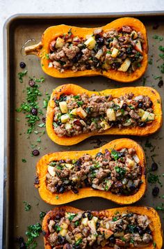 four stuffed squash with meat and vegetables on a baking sheet ready to go into the oven