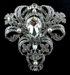 "An old hollywood glamour statement wedding broach featuring ornate and detailed Victorian motifs. This stunning bridal brooch is made of clear swarovski crystals with handwired pearls, set on silver rhodium finish. Broach is big and wide, measures about 3 1/4\" (8.5cm) x 3 1/2\" (9cm) at its widest. View other Victorian inspired accessories https://etsy.me/2uAseFc View all brooch pins at https://etsy.me/1eEBStU * Bride's pics are credit and courtesy of our satisfied bride" Glam Wedding Bouquet, Elegant Pearl Jewelry, Wedding Brooches, Bridal Brooch, Pearl Jewelry Wedding, Bridal Fashion Jewelry, Victorian Wedding, Wedding Brooch, Vintage Style Wedding