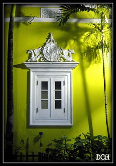 a white cabinet sitting in front of a green wall next to a potted plant