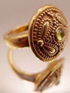 Vintage 14 carat gold Etruscan Revival ring with bezel set peridot gemstone and ornate granulation on medallion style head. Beautiful artisan piece with exquisite attention to detail including etching on underside of head.  Stamped 14K Excellent vintage condition Ring size: US 7 Head diameter: 2.2 cm / 0.7 inch Weight: 2.46 grams ☞ Please view my shipping and sales policies and ✎ Contact me with questions prior to purchase...all sales are final. http://www.etsy.com/shop/Andeebird/policy Elegant Domed Jewelry With Bezel Setting, Gold Cabochon Jewelry For May Birthstone, Gold Byzantine Jewelry With Cabochon, Byzantine Gold Cabochon Jewelry, Byzantine Gold Jewelry With Cabochon, Ornate Gold Filigree Ring, Byzantine Round Hallmarked Jewelry, Gold Byzantine Jewelry With Bezel Setting, Elegant Brass Rings With Cabochon