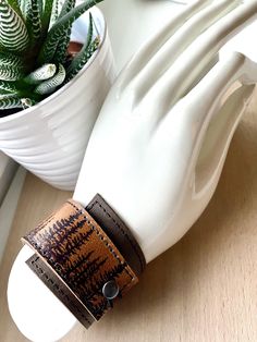 "I've made this wrapping cuff out of soft, scuffy brown and sienna brown leather. The leather has been hand printed with an image using indelible (permanent) ink. Machine stitched, it has an attached elastic that hooks over a button, so this cuff will adjust to fit most wrist sizes 5.75\" to 7\" in circumference. At the narrowest, the width of the cuff is 1.25\" and at the widest it's 2\". Only premium quality leather and supplies are used to handcraft each item. Small imperfections may exist in Adjustable Brown Cuff Bracelet For Everyday, Adjustable Brown Cuff Bracelet With Bracelet Strap, Adjustable Brown Cuff Bracelet With Strap, Brown Adjustable Band Bracelet As Gift, Adjustable Brown Bangle Wristband, Brown Adjustable Bracelets As Gift, Brown Everyday Cuff Bracelet, Everyday Brown Cuff Bracelet, Adjustable Brown Cuff Bracelet