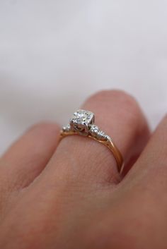 a woman's hand with a diamond ring on top of her finger and an engagement band