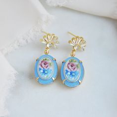 "Cameo Earrings // Flower Earrings // Vintage Earrings // Blue Earrings // Floral Earrings // Art Deco Earrings // Retro Earrings // Boho Bridal Earrings // Oval Earrings  These unique blue cameo earrings blend the beauty of the past with a modern twist for the modern bride. The oval earrings feature matte blue and pink floral motifs surrounded by a golden frame adding a touch of vintage retro style. The fan shaped earring posts are embellished with cubic zirconia and plated with gold. Whether searching for unique wedding earrings or something blue for your next special occasion your beautiful art deco earrings will arrive suitably gift wrapped ready for gift giving. Measurements: The length of the romantic floral cameo earrings hang approx. 1.5\" long Metals: Gold plated 925 sterling silv Art Deco Earrings Bridal, Flower Earrings Wedding, Unique Wedding Earrings, Fan Necklace, Fairy Artwork, Cameo Earrings, Deco Earrings, Earrings Art, Retro Earring