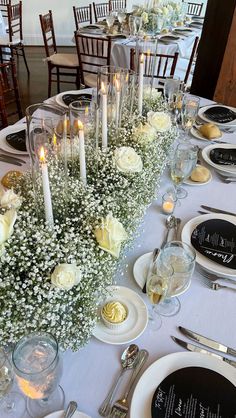 a long table is set with white flowers and candles for an elegant dinner or reception