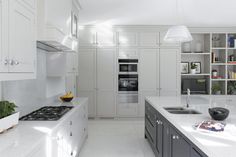 a kitchen with white counter tops and gray cabinets