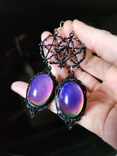 Our latest design is inspired by moody witches.  We've taken black pentacle charms and posited them up with gorgeous color changing mood cabochons made of glass set in an ornate black frame.  Perfect witchy goth earrings! 🥰  - Glass 25x18mm mood color changing with heat cabochons - black pewter pentacle and materials - Stainless steel earrings hooks with rubber backs included. Handmade Black Fantasy Earrings, Handmade Black Fantasy Jewelry, Black Fantasy Dangle Jewelry, Mystical Nickel-free Black Jewelry, Mystical Black Nickel-free Jewelry, Black Fantasy Style Pierced Earrings, Black Fantasy Earrings, Black Fantasy Style Earrings, Black Nickel-free Mystical Jewelry