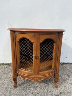 an old wooden cabinet with glass doors on the top and bottom, in front of a white wall