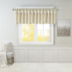 a living room with white walls and curtains on the window sill, along with a chair