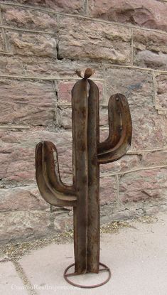 a metal cactus sitting next to a brick wall