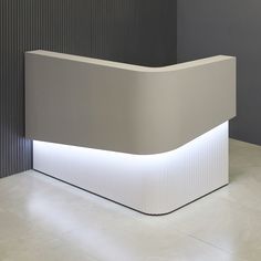 a white reception counter sitting on top of a tiled floor next to a gray wall