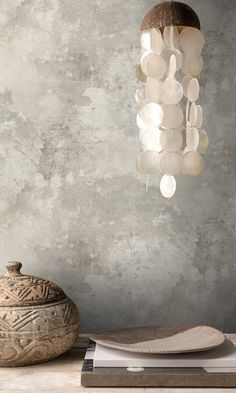 a light fixture hanging from the ceiling next to a bowl and plate on a table